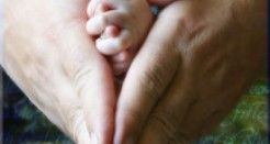 manos de adulto arropando las de un bebe