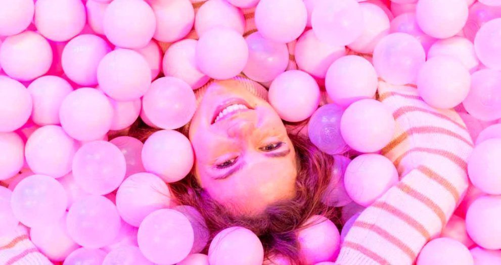 mujer en un parque de bolas rosas