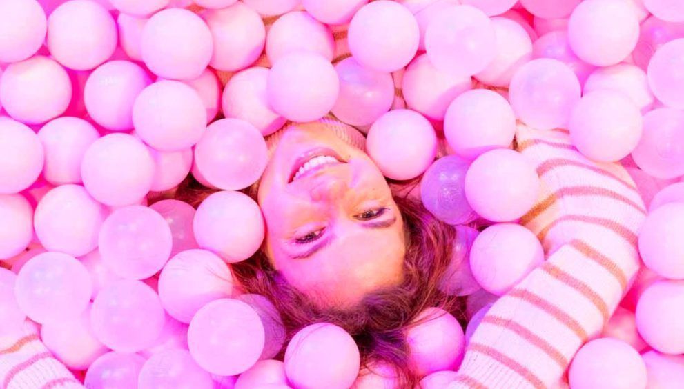 mujer en un parque de bolas rosas