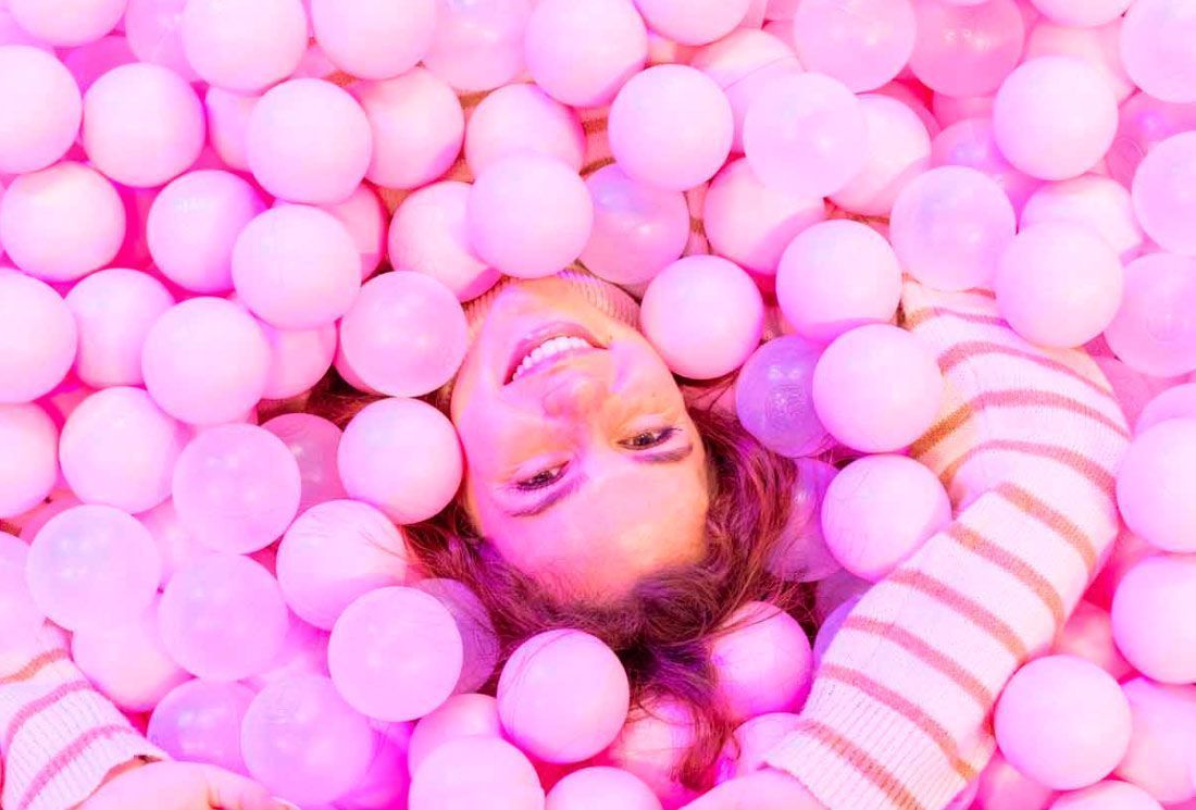 mujer en un parque de bolas rosas