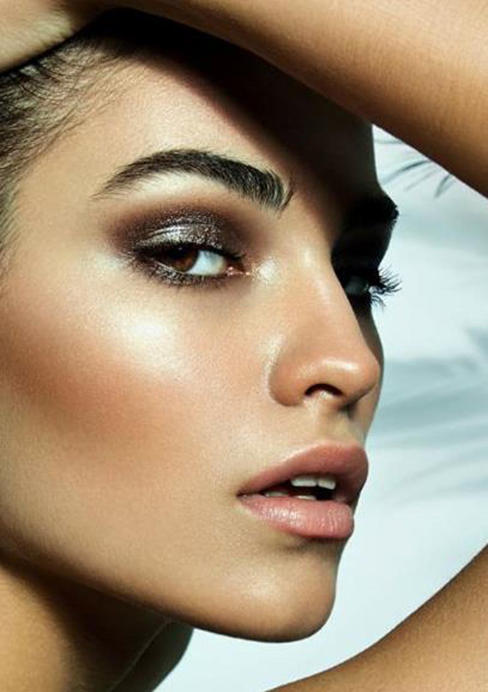 Rostro femenino de perfil mirando a cámara muy maquillado