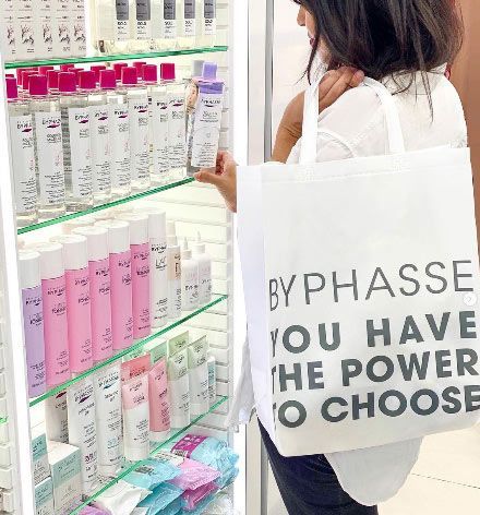 chica mirando productos byphasse, comética a precios bajos, con shoping bag en la que se lee byphasse