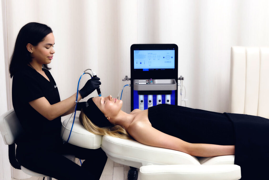 Terapeuta haciendo tratamiento facial con péptidos a chica en camilla